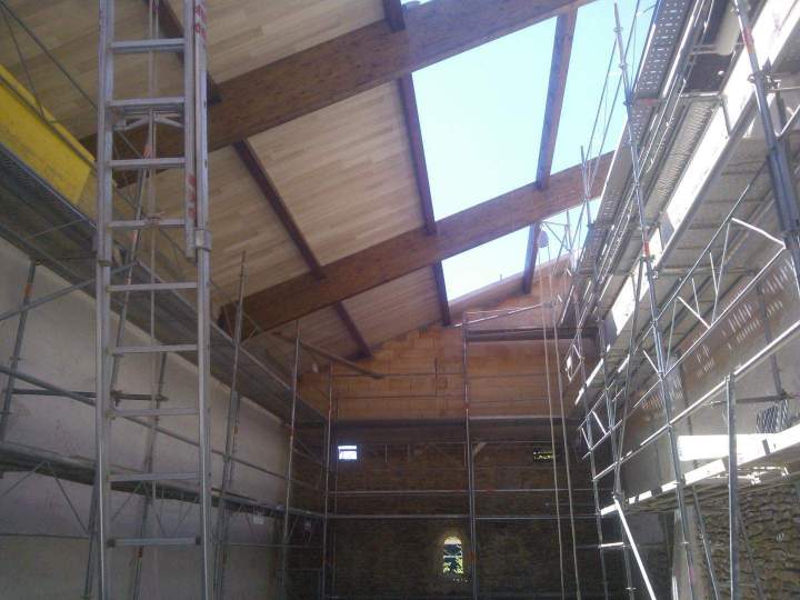 Espace intérieur en rénovation avec plafond bois, échafaudages et mur en pierre Mâcon